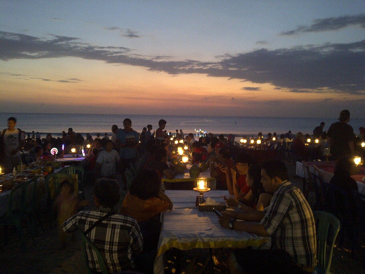 Candlelit dinner tables on Jimbaran Beach at dusk